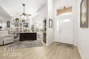 Foyer entrance featuring light wood-type flooring, ceiling fan, and high vaulted ceiling