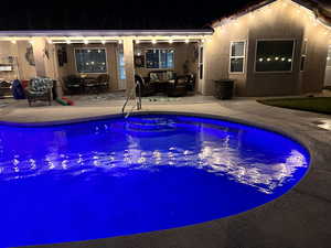 Pool at night featuring outdoor lounge area, a patio, and an outdoor pool
