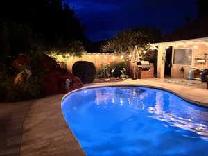 Pool at night with area for grilling and a patio area