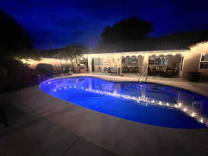 Pool at twilight with outdoor lounge area, a patio, and an outdoor pool