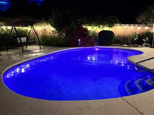 Pool at twilight featuring a patio area and a fenced backyard