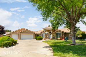 Mediterranean / spanish house featuring stucco siding, a garage, a tiled roof, a front lawn, and concrete driveway