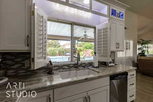 Kitchen featuring stainless steel dishwasher, plenty of natural light, white cabinets, and a ceiling fan