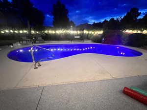 Pool at night featuring a patio
