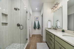 Bathroom with a shower stall, double vanity, wood finished floors, and recessed lighting