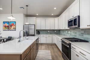 Kitchen featuring stainless steel appliances, light wood-style floors, light countertops, white cabinets, and recessed lighting