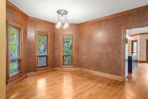 Empty room with ornamental molding and light wood-style flooring