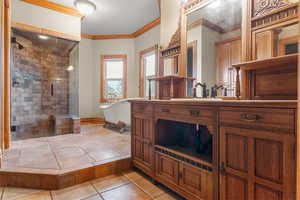 Bathroom with ornamental molding, a shower stall, vanity, light tile patterned floors, and a freestanding tub
