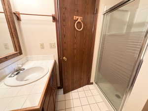 Full bathroom featuring a stall shower, light tile patterned floors, and vanity