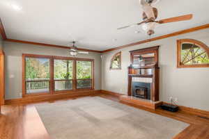 Unfurnished living room with a wood stove, crown molding, and wood finished floors