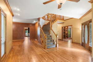 Entrance foyer with ornamental molding, stairs, healthy amount of natural light, light wood-style floors, and a ceiling fan