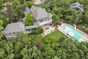 Aerial view of property and surrounding area with a pool and a tree filled landscape