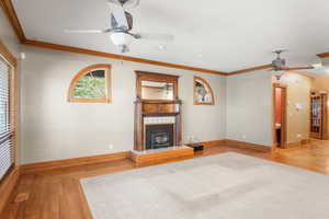 Unfurnished living room featuring crown molding, wood finished floors, a ceiling fan, a wood stove, and recessed lighting