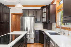 Kitchen featuring stainless steel appliances, light wood-style flooring, hanging light fixtures, light stone counters, and glass insert cabinets