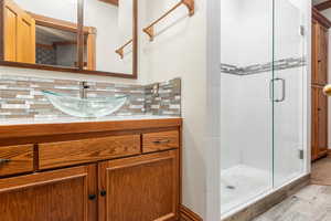 Full bathroom with vanity, a shower stall, tasteful backsplash, and wood finished floors