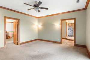 Empty room with ornamental molding, light carpet, and ceiling fan