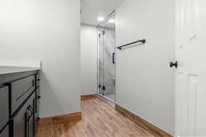 Full bathroom featuring a marble finish shower, wood finish floors, and vanity