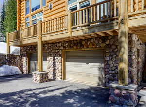 View of property exterior featuring stone siding, a garage, a balcony, and driveway