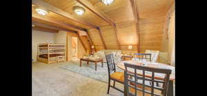 Living area featuring a wood ceiling with exposed beams, carpet floors, and wood walls
