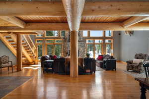Living area with a wooden ceiling with exposed beams, hardwood / wood-style floors, healthy amount of natural light, and stairs