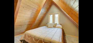 Bedroom featuring carpet flooring, wooden ceiling, and lofted ceiling