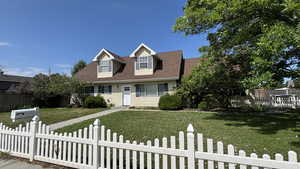 Cape cod home with a fenced front yard and roof with shingles