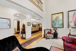 Living area with a chandelier, wood finished floors, arched walkways, and a towering ceiling