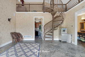 Staircase with a towering ceiling and stone tile flooring