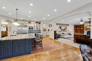 Kitchen with arched walkways, white cabinets, light wood-style floors, built in appliances, and recessed lighting