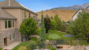 View of property's community with an area to practice putting, a mountain view, and a yard