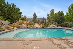 View of pool with a mountain view, an outdoor living space, a patio, and a water slide