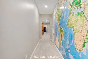 Hall with arched walkways, recessed lighting, and light colored carpet
