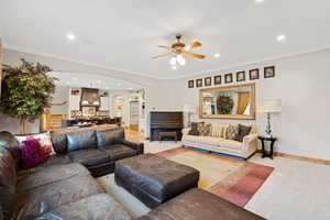Living area featuring arched walkways, ornamental molding, carpet floors, recessed lighting, and a ceiling fan