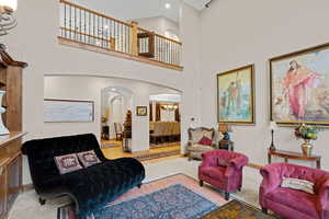 Living room featuring arched walkways, a towering ceiling, carpet flooring, and a chandelier