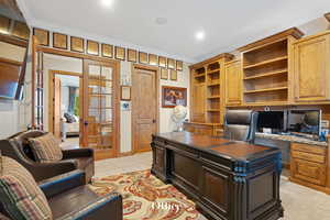 Home office featuring light carpet, crown molding, built in study area, recessed lighting, and french doors