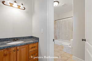Full bathroom with vanity, shower / bath combo with shower curtain, and tile patterned floors