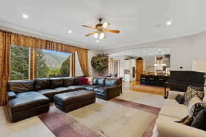 Living room with arched walkways, ornamental molding, recessed lighting, a ceiling fan, and a mountain view