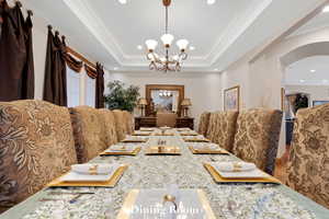Dining room featuring arched walkways, a chandelier, recessed lighting, crown molding, and a raised ceiling