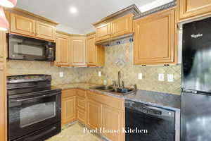 Kitchen with black appliances, backsplash, and stone counters