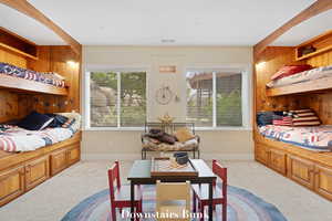 Carpeted bedroom with wooden walls and baseboards