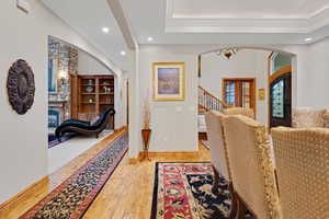 Corridor featuring crown molding, light wood-style floors, arched walkways, recessed lighting, and a chandelier