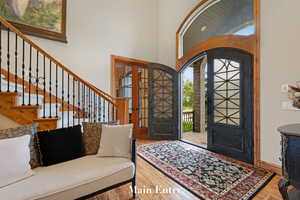 Entryway with stairway, a towering ceiling, wood finished floors, and french doors