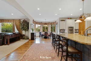 Kitchen with light stone counters, recessed lighting, white cabinetry, light wood-style floors, and decorative light fixtures