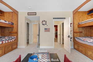 Bedroom featuring wooden walls and light carpet