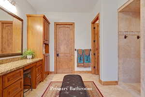 Bathroom featuring a tile shower, vanity, and tile patterned flooring