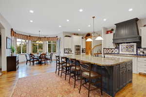 Kitchen with tasteful backsplash, light stone countertops, white cabinetry, decorative light fixtures, and recessed lighting