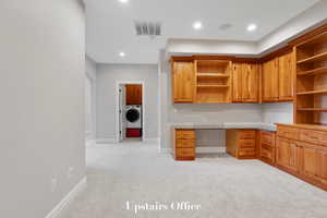 Unfurnished office featuring light carpet, built in desk, recessed lighting, washer / clothes dryer, and arched walkways