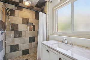 Bathroom with plenty of natural light, tiled shower, and vanity
