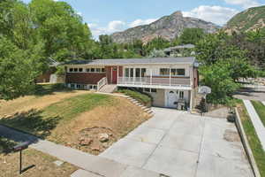 Ranch-style house with stairway, a front yard, concrete driveway, a mountain view, and covered porch