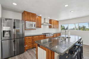 Kitchen featuring appliances with stainless steel finishes, light wood finished floors, brown cabinets, backsplash, and recessed lighting